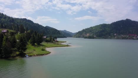 aerial landing low altitude moving shot along lake front with valley in the background