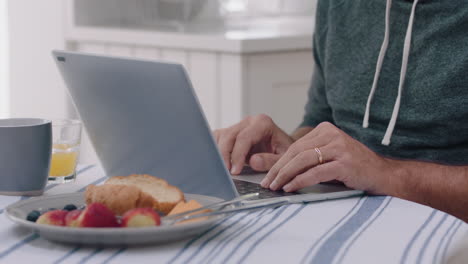 close-up-hands-man-using-laptop-computer-at-home-typing-messages-browsing-online-enjoying-working-in-morning-at-breakfast-4k-footage