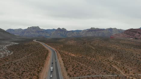 aerial drone shot of a desert highway with mountains in the background