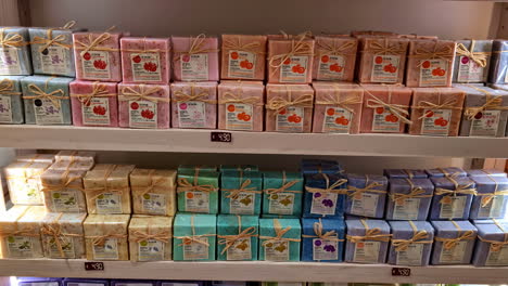 rows of colorful, handmade soaps neatly displayed on a shelf with price tags in a shop in chania, greece
