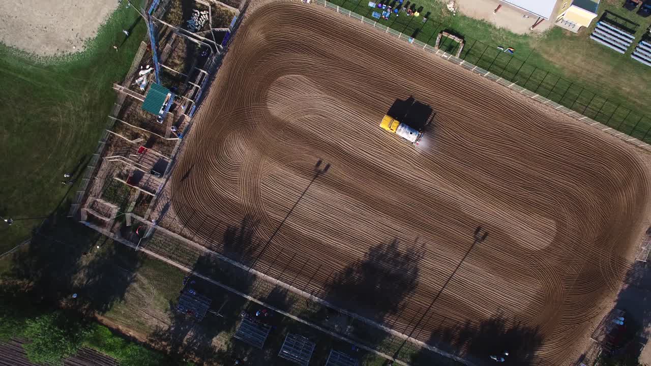 Aerial ascend to very high angle to reveal patterns mad by water truck wetting down groomed dirt arena, Kansas, Missouri