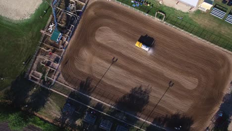 aerial ascend to very high angle to reveal patterns mad by water truck wetting down groomed dirt arena, kansas, missouri