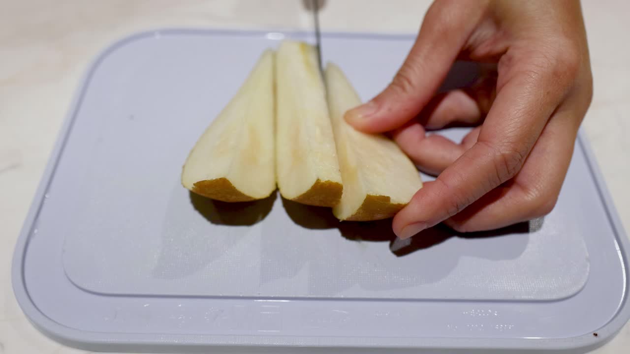 Mano che affetta una pera su un tagliere