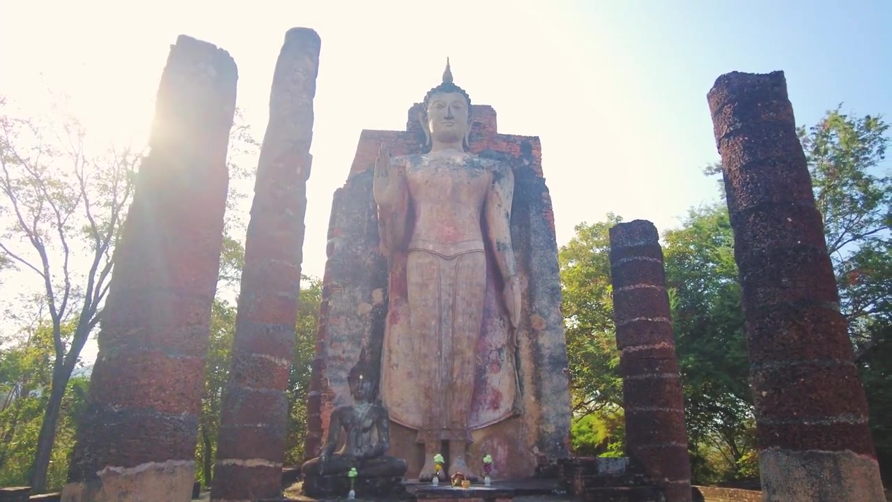 Tượng Phật đứng khổng lồ bên ngoài tàn tích cổ của Wat Maha That. Góc rộng, lóe sáng mặt trời, Di sản Thế giới UNESCO.