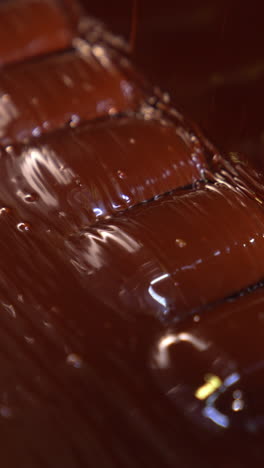 candies come out from the flow of chocolate. sweets deepened in a thick layer of chocolate. close up. vertical video