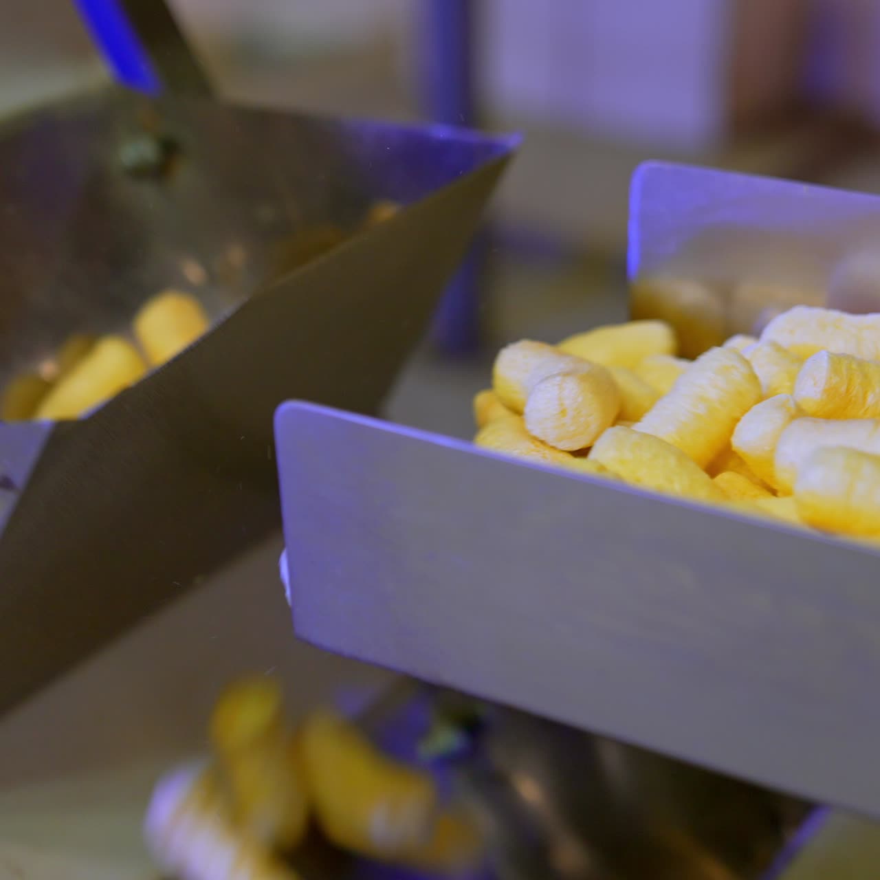 Manufacturing sweet snacks at modern factory. Delicious crispy maize sticks falling on conveyor belt. Close up