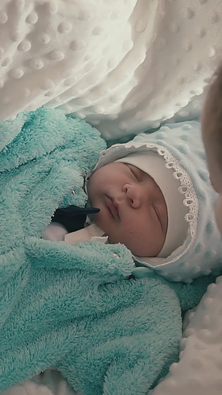 cute sister with plait kisses funny junior brother sleeping on soft blanket on couch in light room close view
