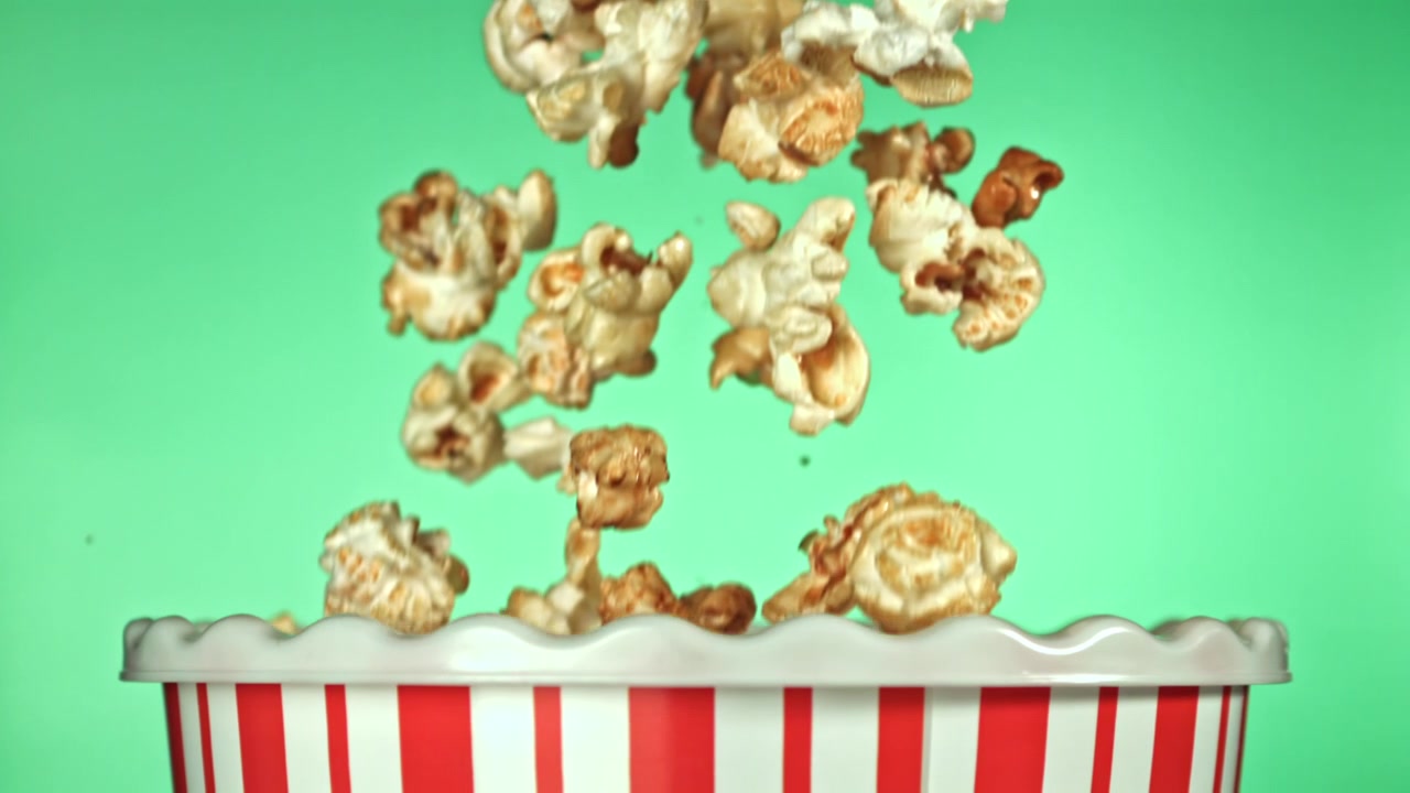 Popcorn che cadono al rallentatore in un secchio a strisce rosse e bianche