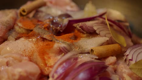 close up of raw chicken with spices, onions, and cinnamon sticks