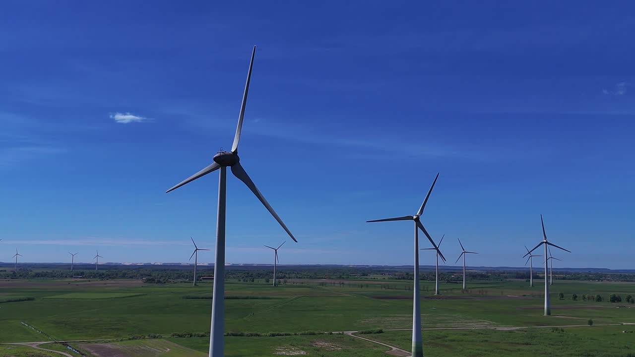 ветряные турбины вращаются в солнечный день на огромном зеленом поле, ясное голубое небо над головой