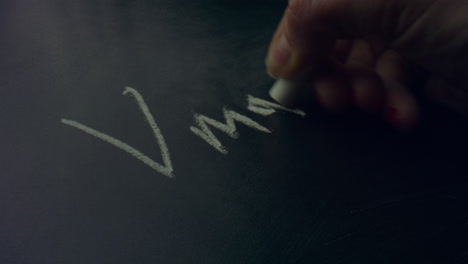 woman hand holding piece of chalk. unknown person writing equation on chalkboard