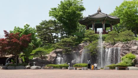 Koreanische-Frau-Mit-Kleinen-Kindern-Steht-Neben-Wasserbrunnen-Und-Wasserfall-Im-Kindermuseum-Der-Provinz-Gyeonggi