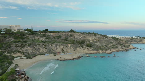 The-coastline-near-Konnos-Beach,-captured-from-an-aerial-perspective,-shows-the-rugged-beauty-of-Cyprus's-shoreline-with-a-mix-of-rocky-outcrops,-lush-vegetation,-and-the-azure-Mediterranean-Sea