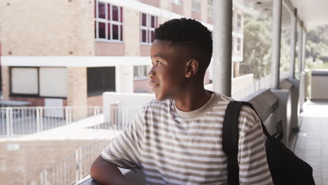 smiling student with backpack standing outside school building, enjoying break time