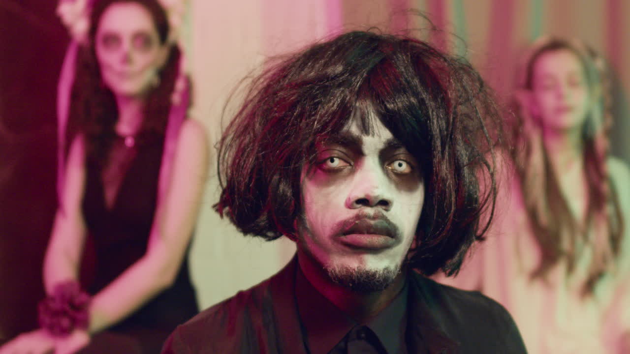 мужчина смотрит на камеру на вечеринке на хэллоуин.