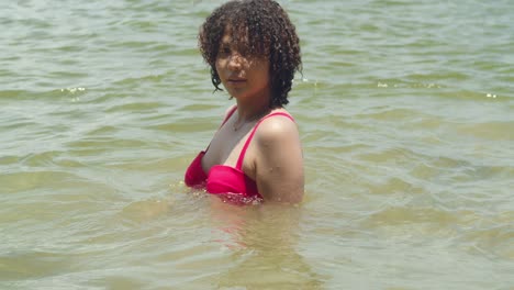 Basking-in-the-tropical-vibes,-a-Latina-with-curly-locks-looks-stunning-in-a-sexy-beach-ensemble