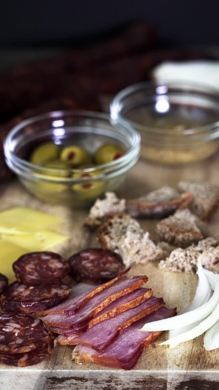 Vertical video from hand taking bread and beacon slice from chopping board . Various other ingredients are placed on a wooden board