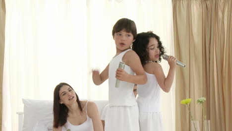 family singing and dancing on bed with microphones