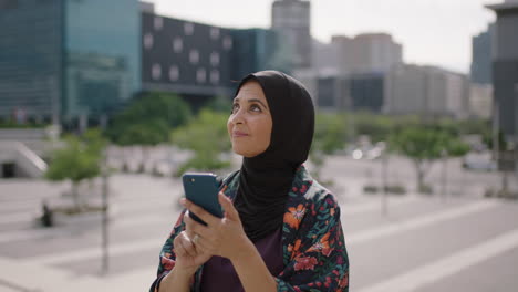 portrait-of-beautiful-mature-muslim-woman-texting-browsing-using-smartphone-social-media-app-enjoying-chatting-in-sunny-urban-city-background