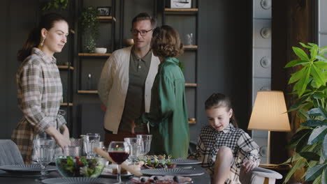 familia feliz sentada en la mesa del comedor y lista para comer juntos