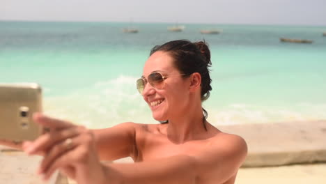 fotografía de una chica morena con gafas de sol tomando una selfie en la playa de zanzíbar, tanzania