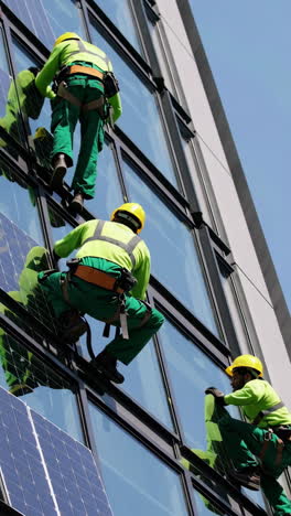 window cleaners on a building with solar panels