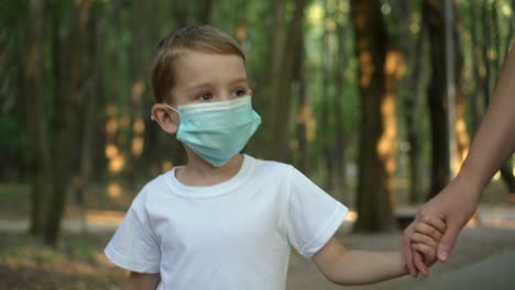 madre e hijo con máscaras médicas caminan en el parque 01
