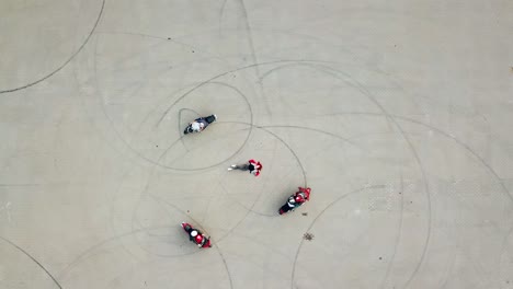 Three professional bikers on their motorcycles riding on a road in the form of a circle. Smiling beautiful young woman lying in the centre of the pavement. Camera moves top down.