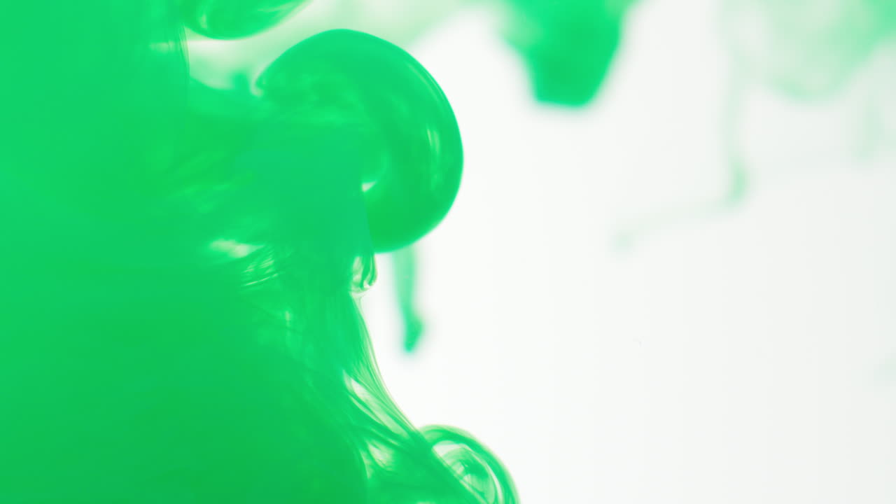 녹색 페인트 또는 염료가 색 배경에 물에 떨어지면 회전하는 다채로운 연기 배경을 만니다.
