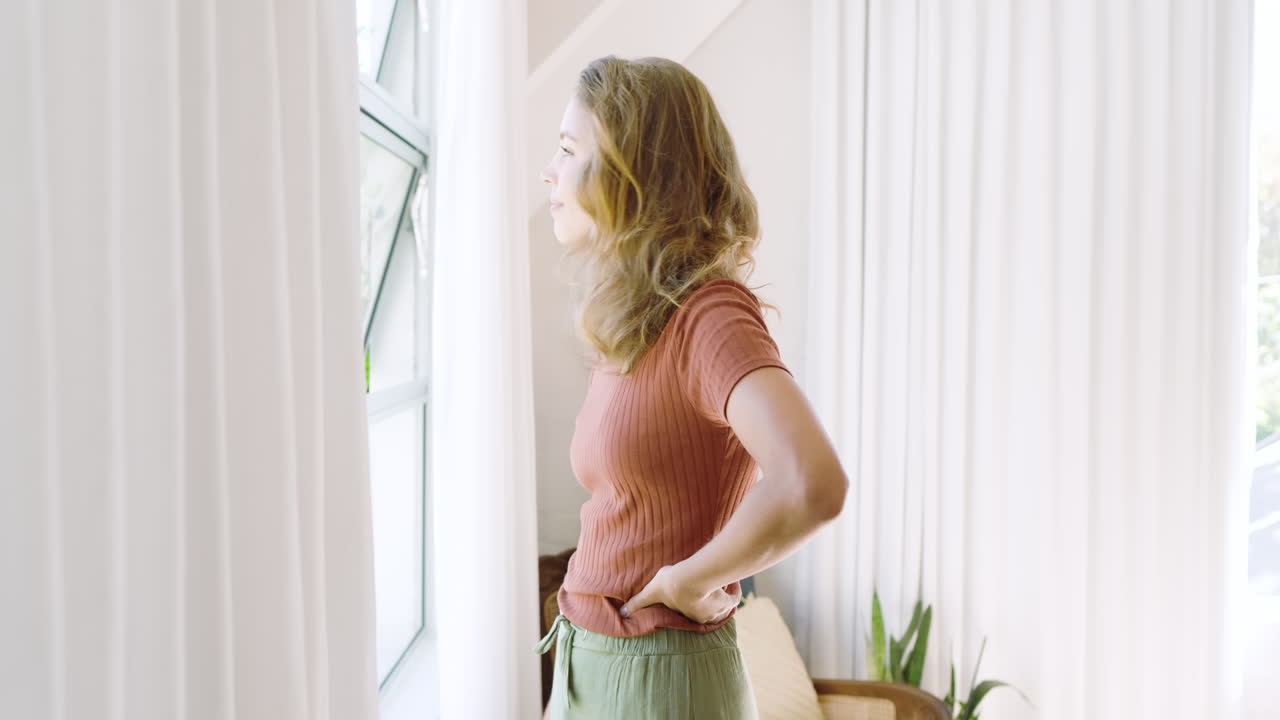 Happy diverse couple standing by window, embracing and enjoying bright sunny day indoors, at home