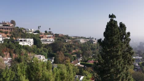 toma aérea de las mansiones de beverly hills en la ladera con neblina y aire ahumado que nubla el valle en el fondo