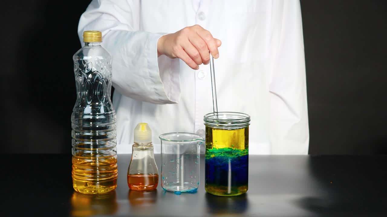 과학자가 다채로운 액체 실험을 수행하여 다양한 액체와 는 막대기를 사용하여 용암 램프 효과를 만니다.