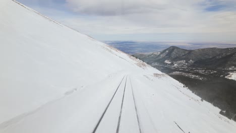 cog railway tracks on snowy slope of manitou and pikes peak in colorado, usa. wide drone shot