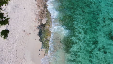 beautiful-crystal-clear-turquoise-ocean-and-empty-white-sand-beach-in-Mexico,-aerial-top-down