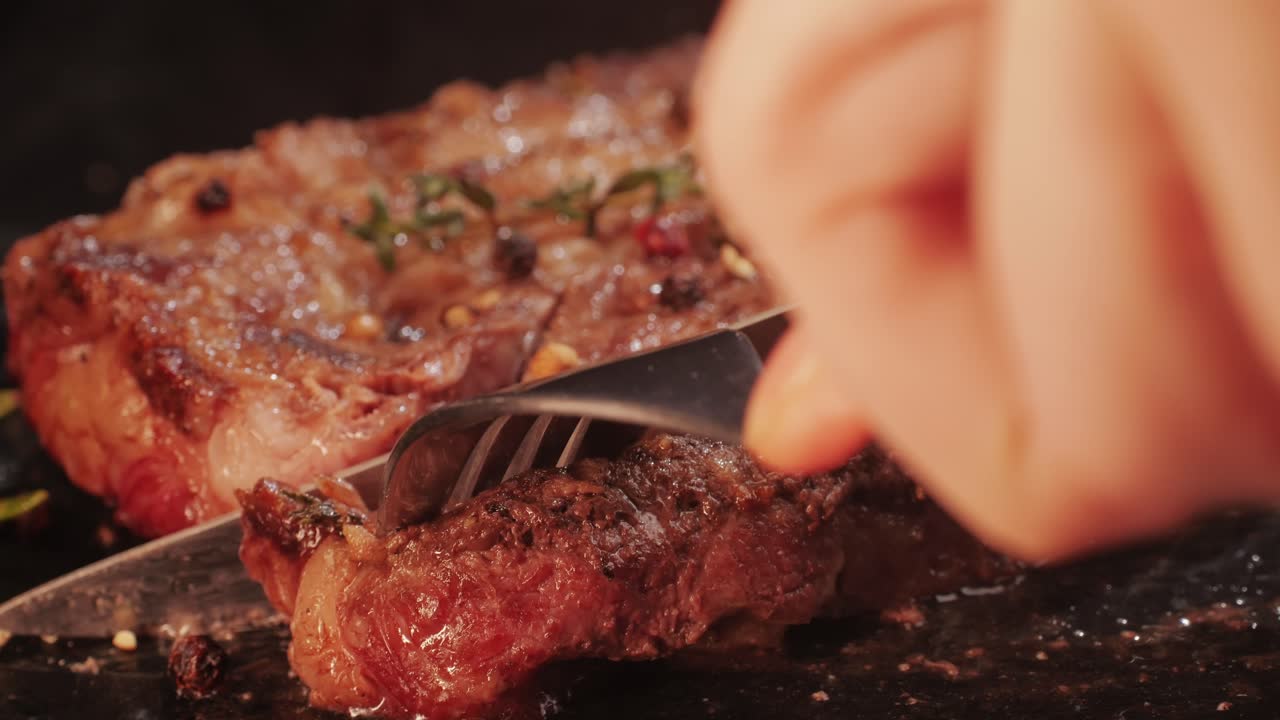 Fresh marbled beef with pepper, salt and rosemary close-up macro. Cutting with knife juicy steak on plate. Premium organic wagyu meat. High quality 4k footage