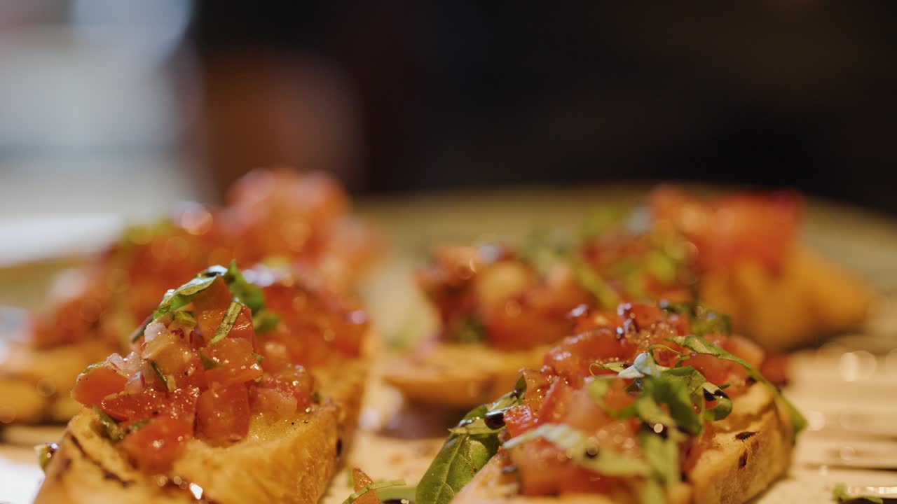 Close-up of hand picking bruschetta from plate, warm lighting, shallow depth of field