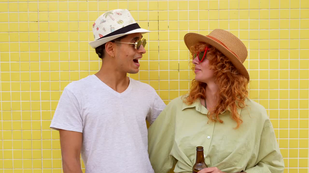 Couple enjoying beers in front of a yellow wall