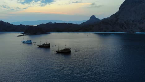 Tres-Barcos-Turísticos-Anclados-Frente-A-La-Costa-De-La-Isla-Padar-En-El-Parque-Nacional-De-Komodo,-Indonesia,-Durante-La-Noche,-Mostrando-La-Belleza-Salvaje-Del-Entorno.