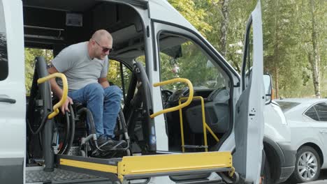 a man in a wheelchair on a lift of a vehicle for people with disabilities. lifting equipment for people with disabilities - man in wheelchair near the vehicle