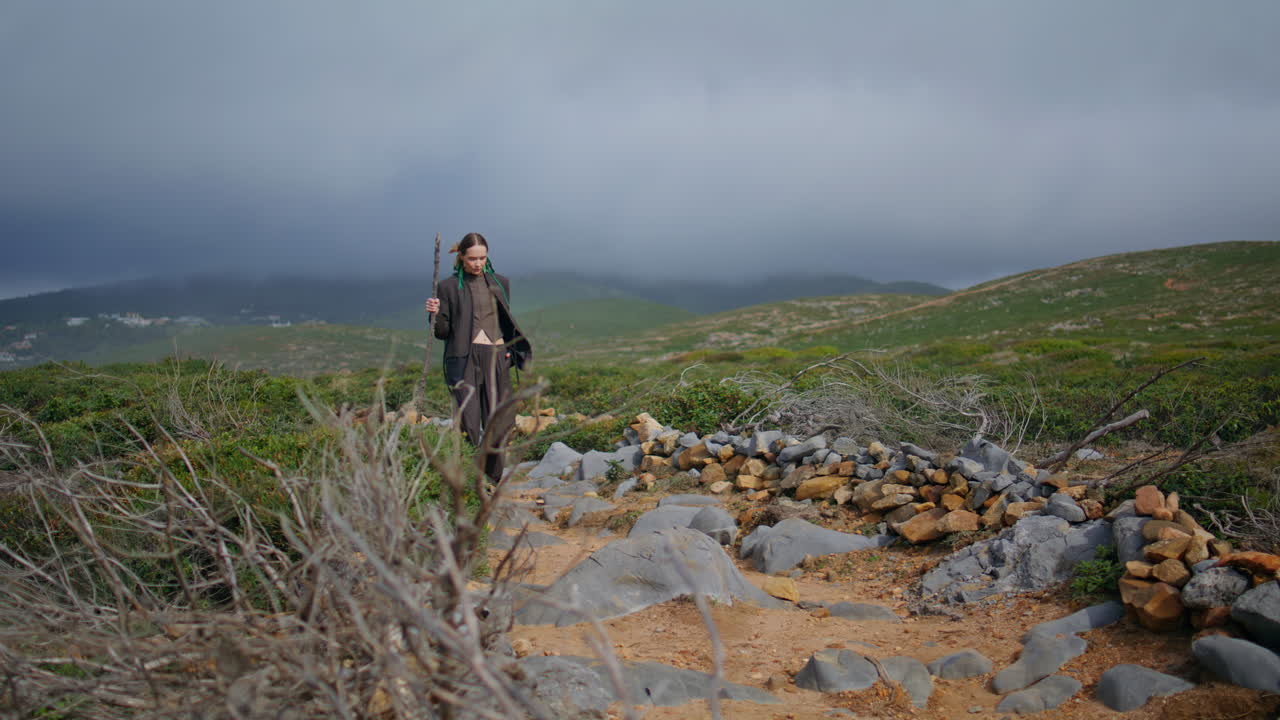 mujer serena caminando por las montañas en un cielo nublado. turista caminando por la colina verde