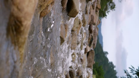 vertical of a clear stream running through stone boulders abundant river flowing in slow motion