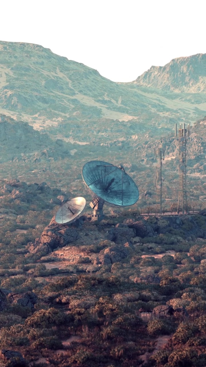 Twee grote schotelantennes staan op een heuvel omringd door bergen