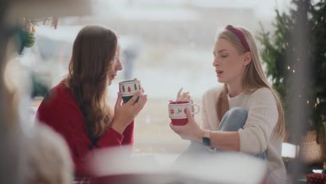 woman talking to sister having coffee during christmas at home