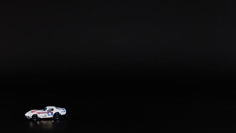 two toy cars moving across a dark background