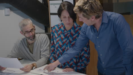 mature architects discussing floor plans at office meeting