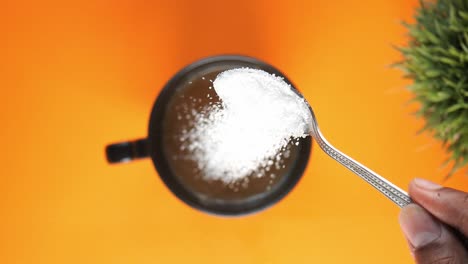 slow motion of pouring white sugar in a coffee cup , top view ,