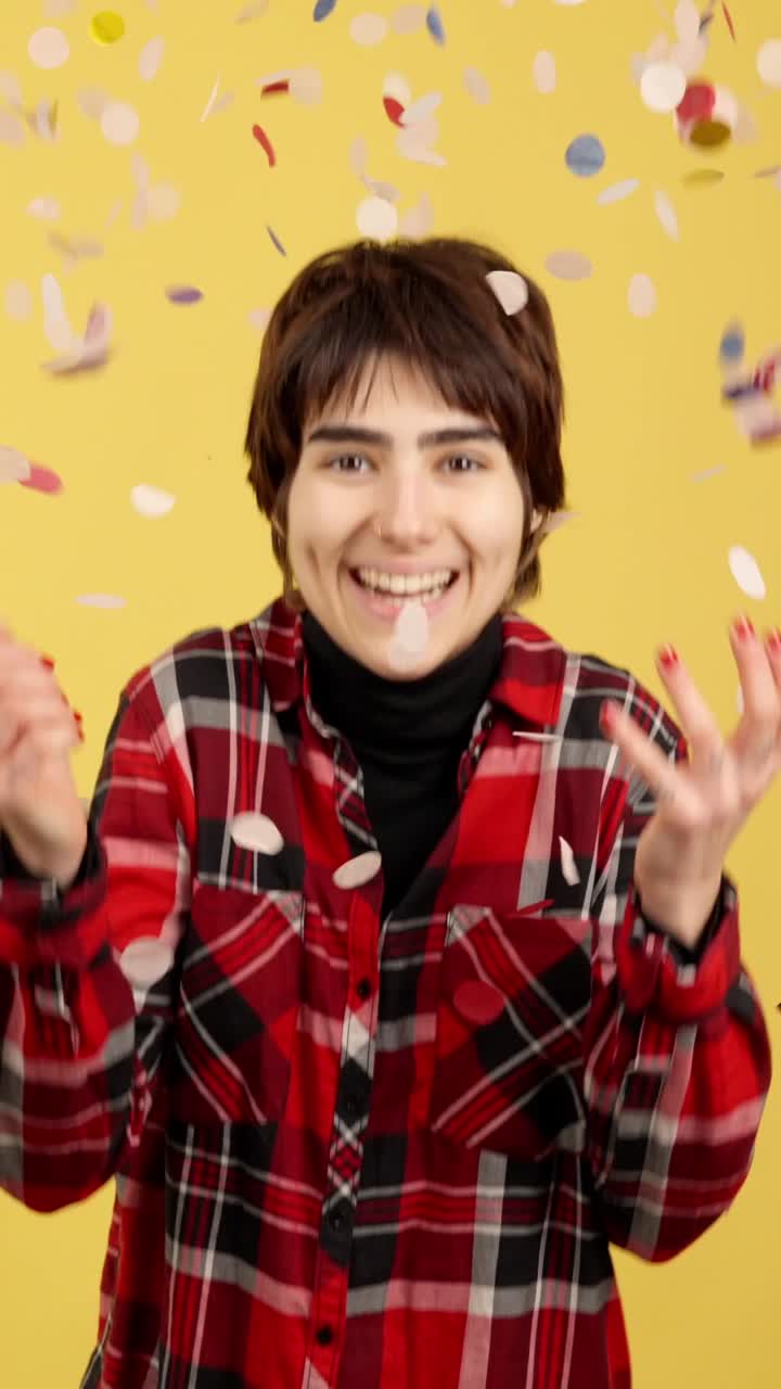 Joyful person celebrating with falling confetti on a yellow background