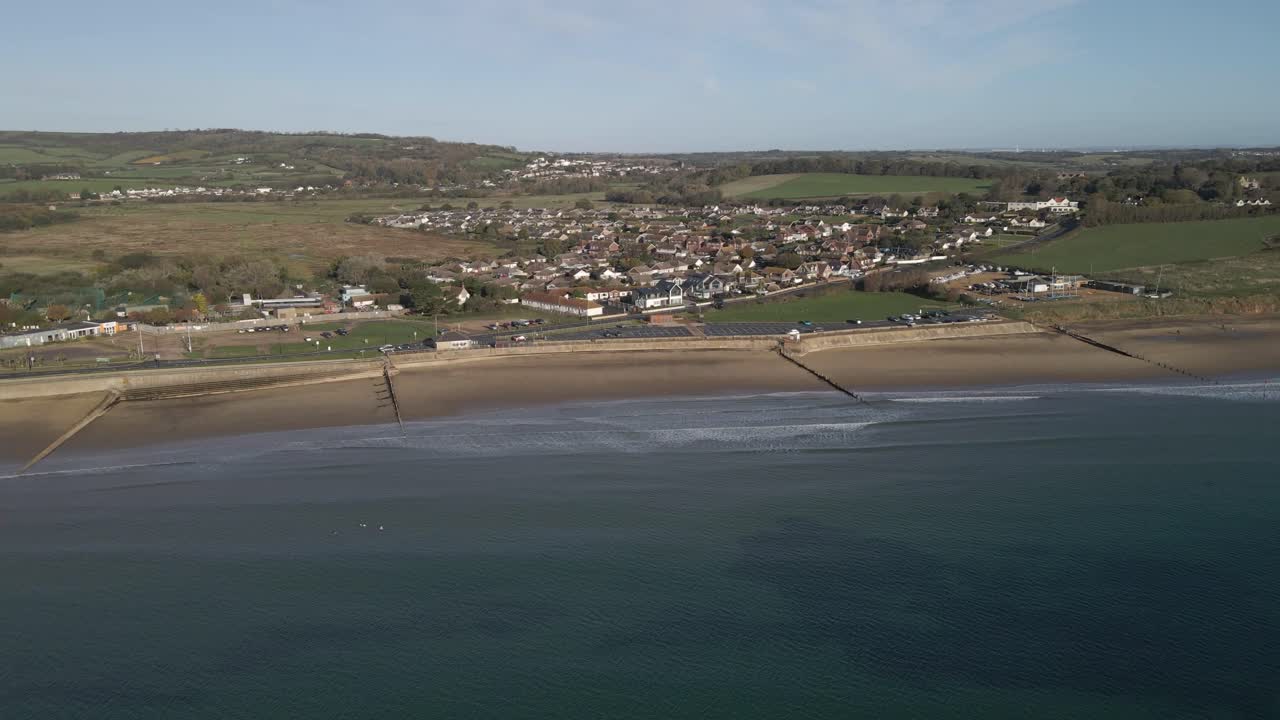 Aerial view of Sandown a seaside resort and civil parish on the south-east coast of the Isle of Wight, England. Drone rotating to the left over the sea showing the yellow beach and the buildings. 4K