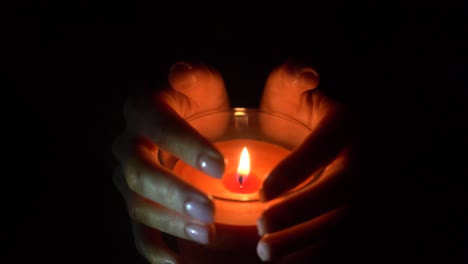 close up of woman hand lighting candles in the dark night at home