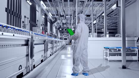 full body back view of asian male scientist use green screen tablet while standing in water factory, water bottles on production line